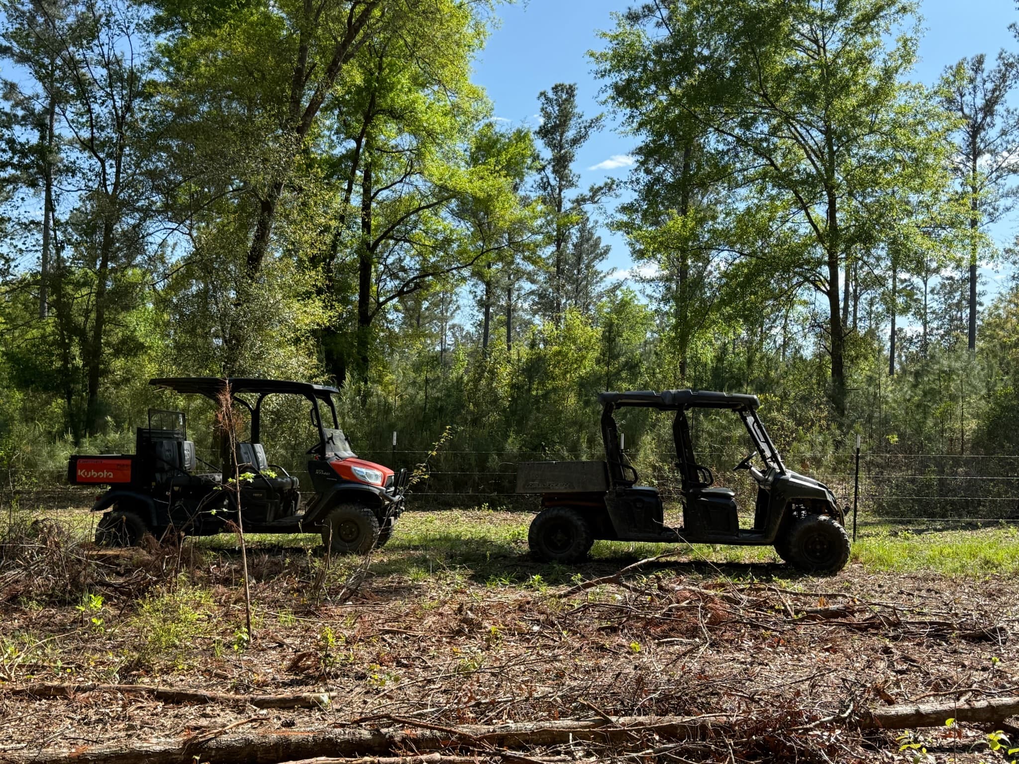 UTVs parked in a cleared woodland at the ranch